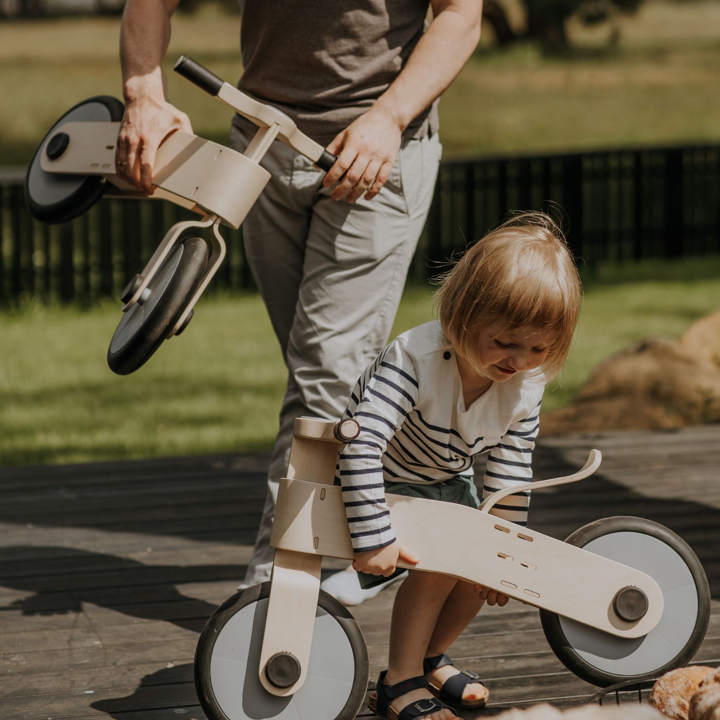 2 year old toddler riding a wooden balance bike outdoors